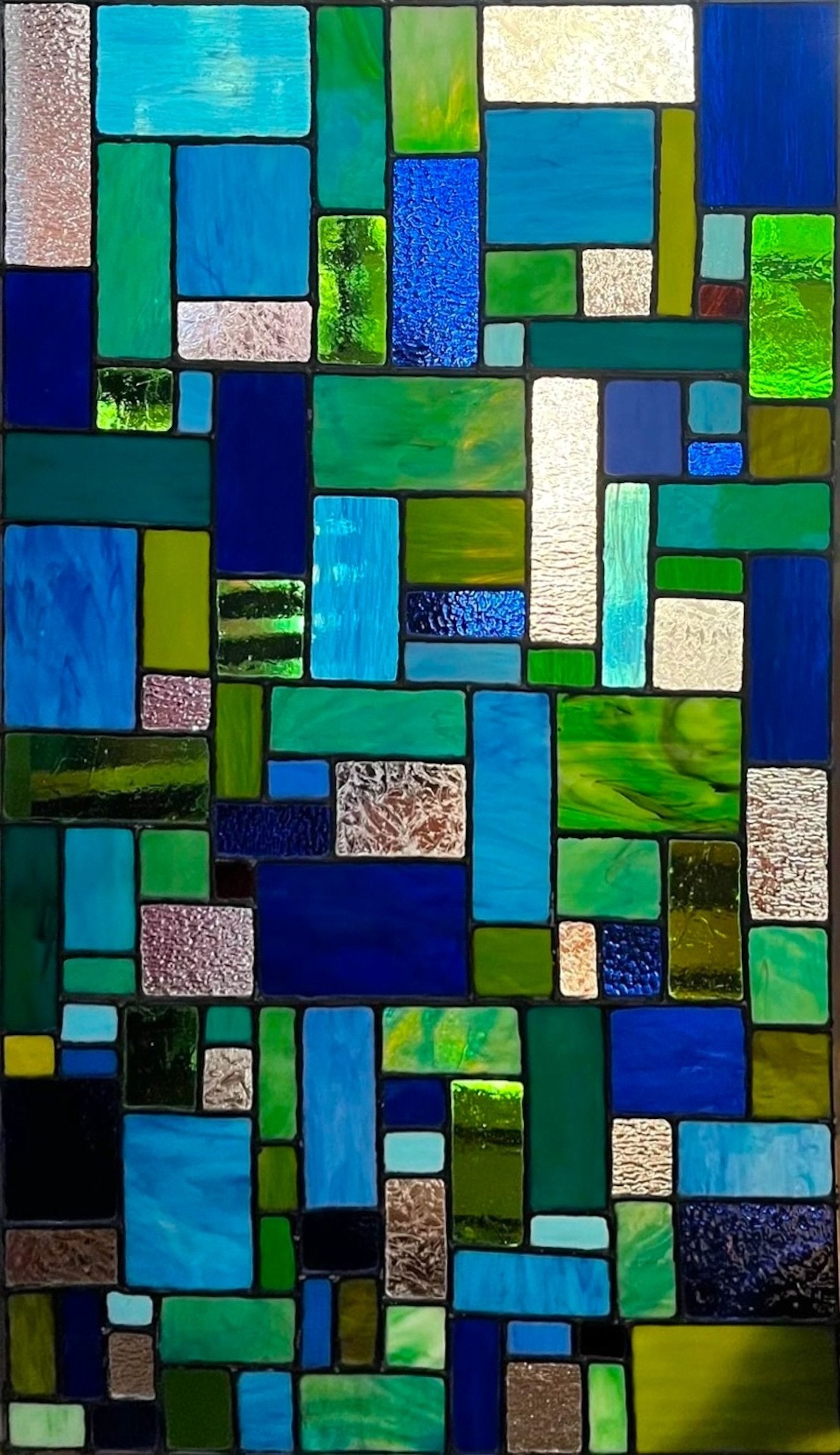 Abstract blue and green geometric stained glass panel